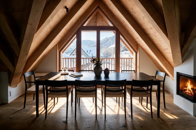 Wooden dining table with chairs, a fireplace, and windows with views of the snowy mountain.