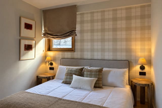 Bedroom with a double bed, wooden nightstands, and a window with a blind.