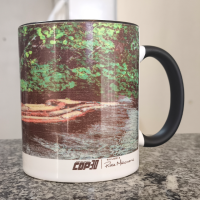 Foto de uma caneca temática da COP30 ilustrada com uma fotografia da floresta