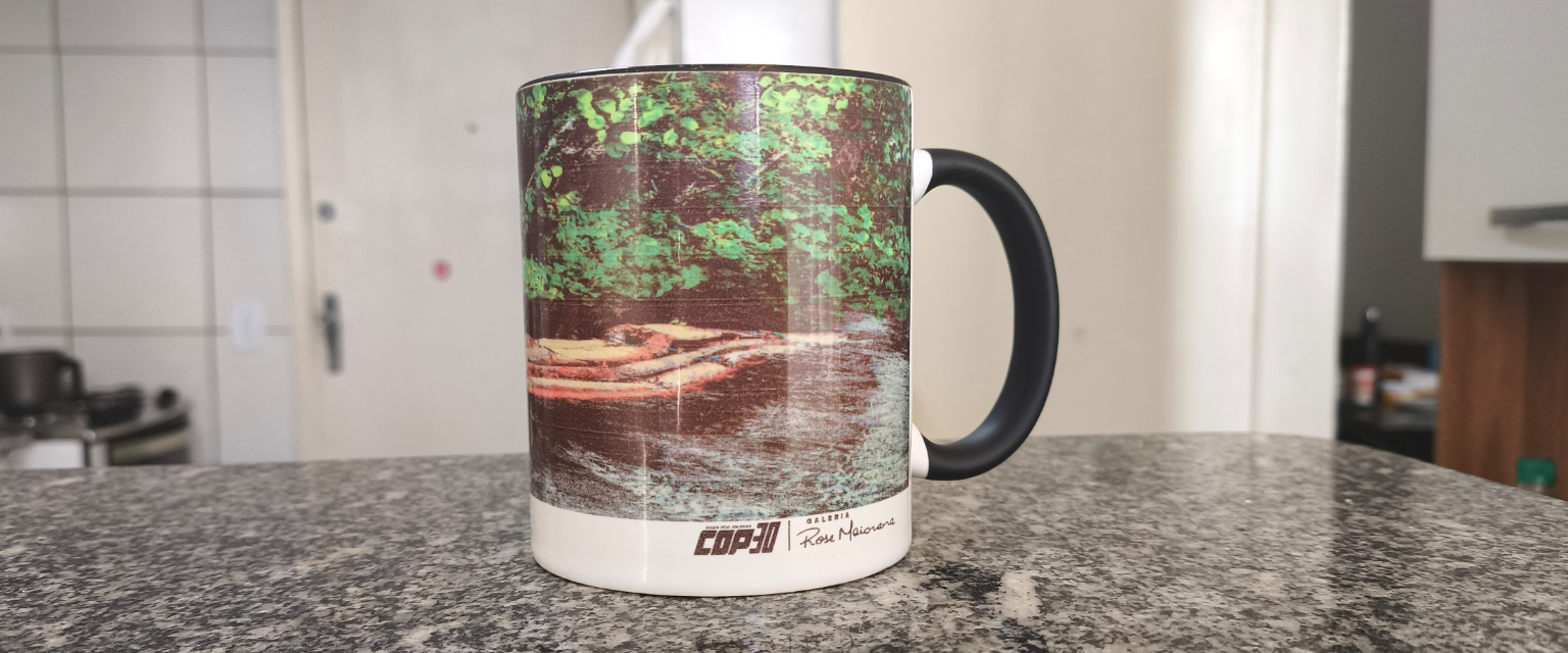 Foto de uma caneca temática da COP30 ilustrada com uma fotografia da floresta