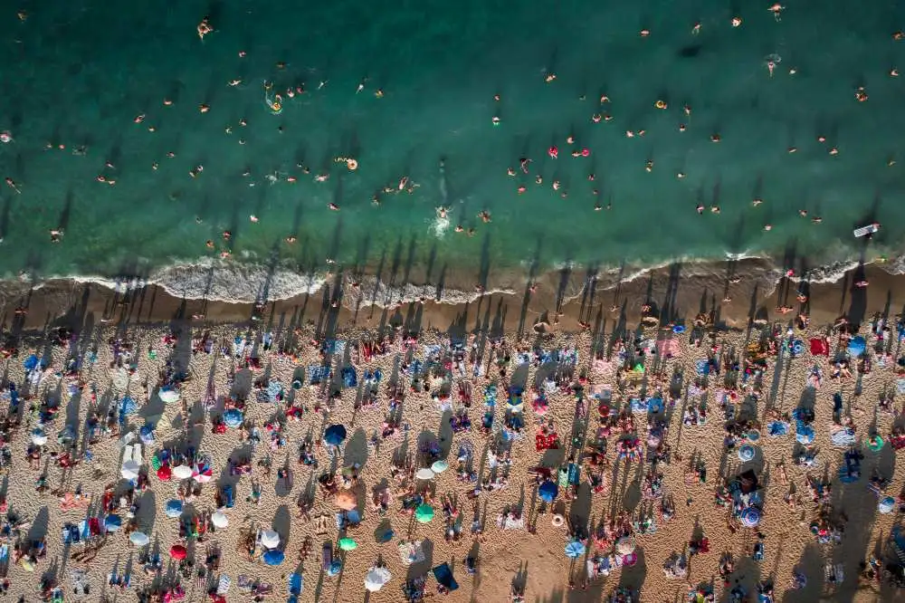 Spiaggia affollata di turisti, a contrasto con le foto perfette sui social network