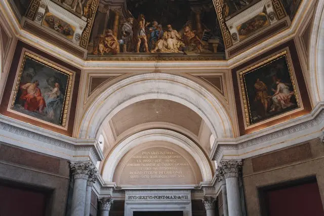 Volte e arcate marmoree con affreschi e quadri dorati all’ingresso di un palazzo espositivo a Roma