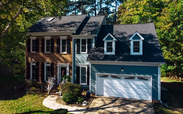 Blue two-story home with a brand-new asphalt shingle roof by Baker