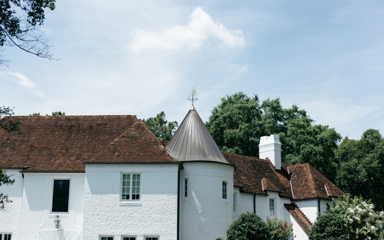 Clay tile roof and copper turret on a white Charleston home by Baker