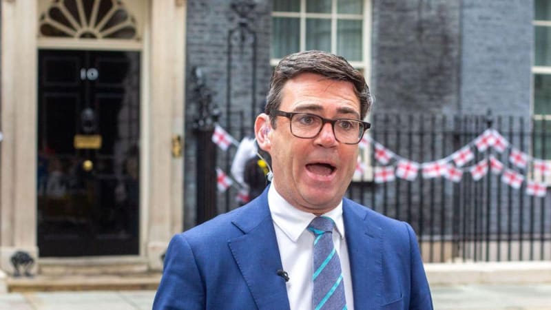 A man in a blue suit and striped tie speaking outside 10 Downing Street in London, with England flag bunting visible in the background.