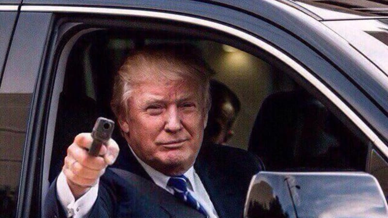 Manipulated or staged photo appearing to show a man in a suit pointing a handgun out of a black vehicle window. The image appears to be digitally altered.