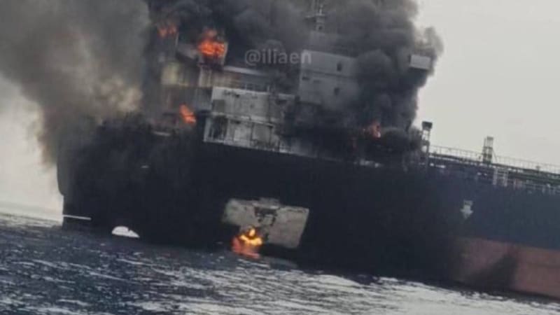 A large tanker or cargo ship engulfed in flames at sea, with thick black smoke billowing from the superstructure and visible fire at multiple points on the vessel.