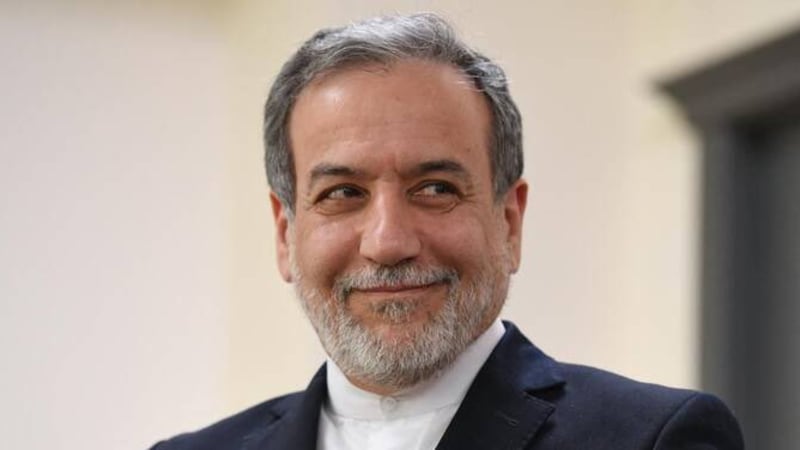 A middle-aged man with gray hair and a trimmed gray beard, wearing a dark suit and white shirt, smiling and looking to the side in what appears to be a formal or diplomatic setting.