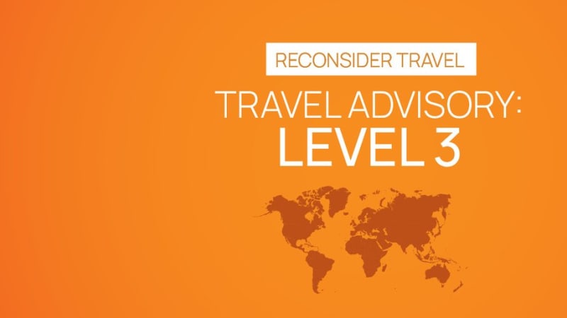 Orange infographic displaying a Level 3 travel advisory with the text 'Reconsider Travel' and a world map silhouette in the background.
