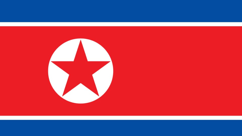 The national flag of North Korea (DPRK), featuring horizontal blue and red stripes separated by thin white lines, with a red five-pointed star inside a white circle on the left side.