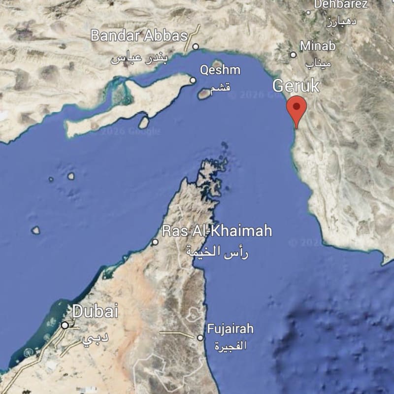 Google Maps satellite view of the Strait of Hormuz region showing a red pin on Geruk, Iran, with visible labels for Bandar Abbas, Qeshm, Dubai, Ras Al-Khaimah, Fujairah, and Sohar.
