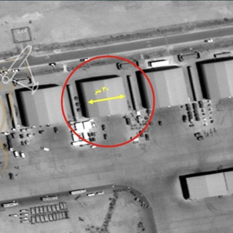Satellite imagery of an industrial or military facility showing large warehouse-like structures with a red circle annotation and a yellow arrow indicating a 30-meter measurement, with Persian/Arabic text labeling.
