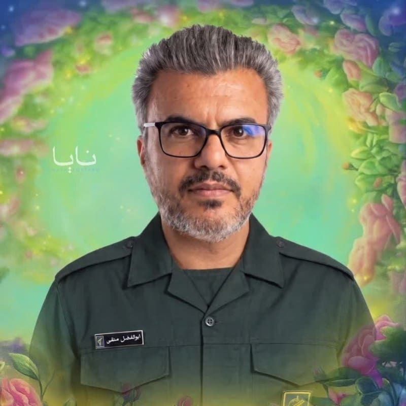 A martyrdom memorial poster featuring a middle-aged man in an IRGC (Islamic Revolutionary Guard Corps) green military uniform and glasses, surrounded by digitally added flowers and a glowing background, with Persian text identifying him as Pasdar Shahid Abolfazl Mottaghi.