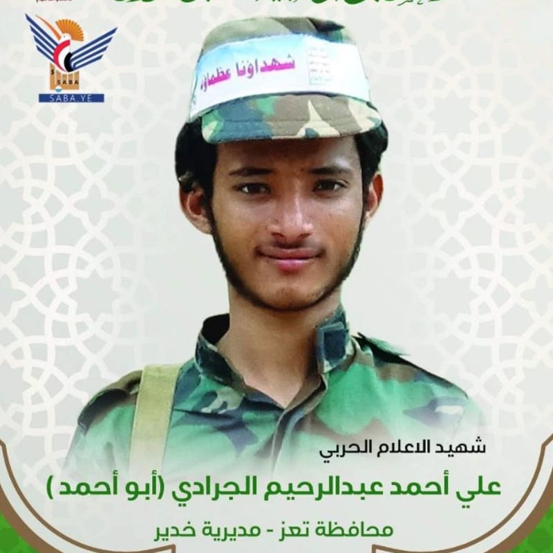 A martyrdom memorial poster featuring a young man in military camouflage uniform and headband with Arabic text. The poster includes Arabic text identifying him as Ali Ahmad Abdulrahim Al-Jaradi from Taiz governorate, with Houthi (Ansar Allah) branding and logos.