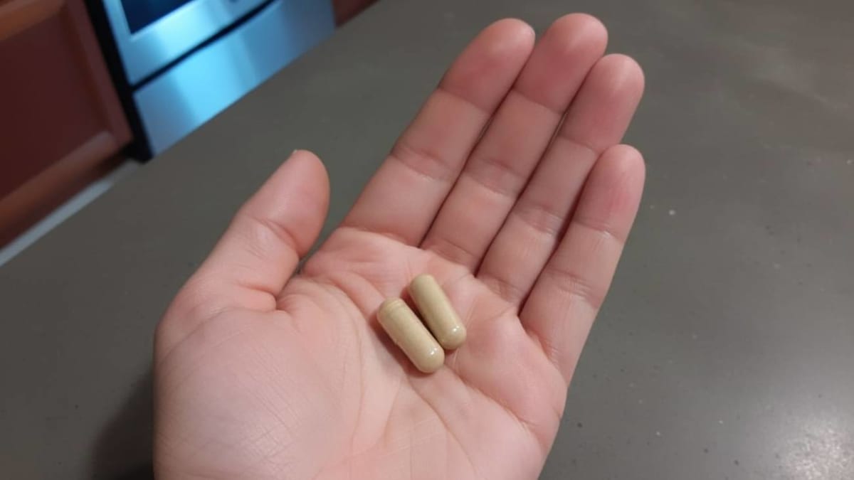 Two brown capsules resting in the palm of a hand