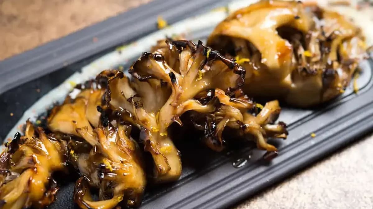 Grilled maitake mushrooms on a plate with golden-brown seared edges
