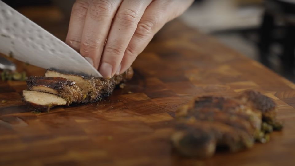 Cutting cooked lion's mane mushroom steak on a chopping board