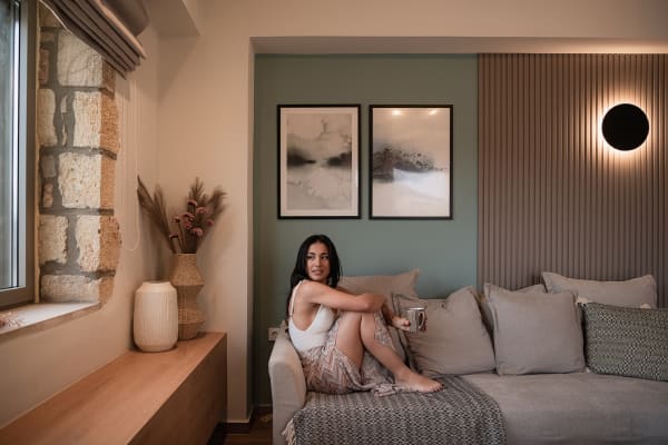 Cozy living room detail featuring a comfortable sofa with pillows, modern wall paneling, abstract artwork, and an original stone wall element.