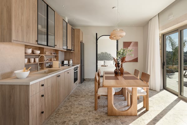 Minimalist kitchen and dining area with light wood cabinetry, a matching wooden table, and earthy decorative accents.