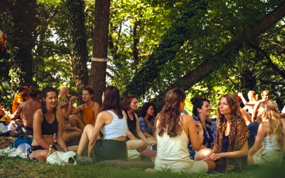 Teilnehmer eines Conscious Celebration Festivals sitzen zusammen in der Natur