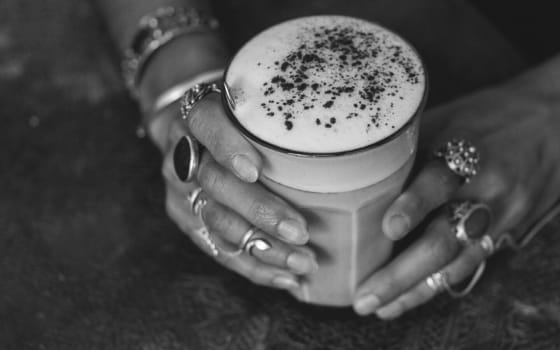 Foto schwarz-weiß Frauenhände halten ein Glas mit Chai Latte