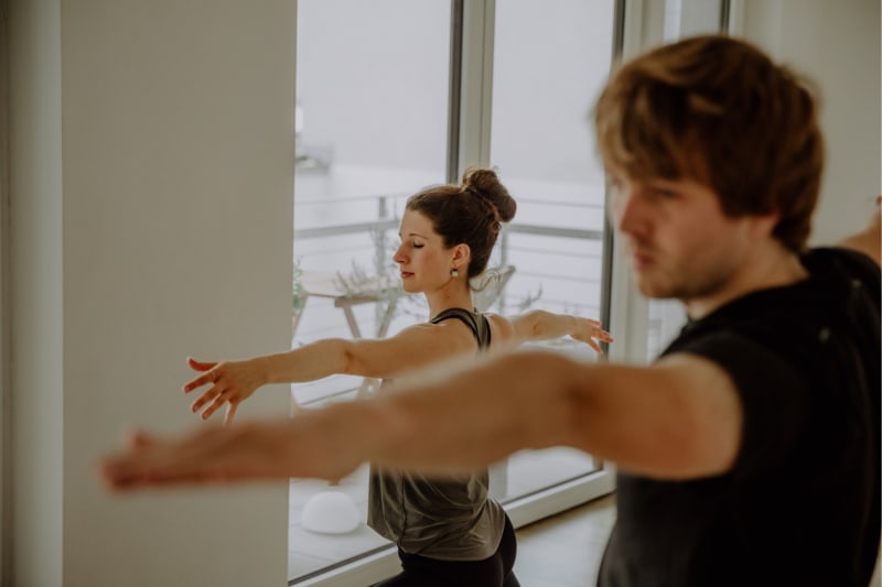 Ein Frau und ein Mann bei der Yoga Pose Krieger 2