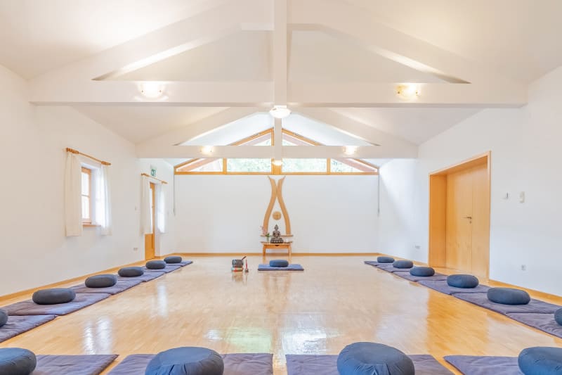 Der untere Meditationsraum im Seminarzentrum Domicilium mit Deckenbalken und blauen Sitzkissen