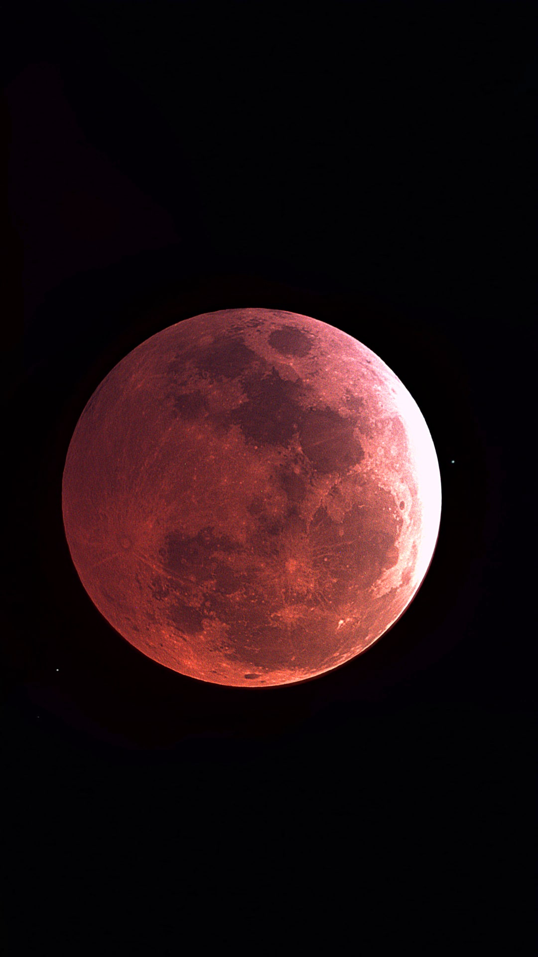 The Moon fully inside Earth's shadow, glowing deep red against a black sky