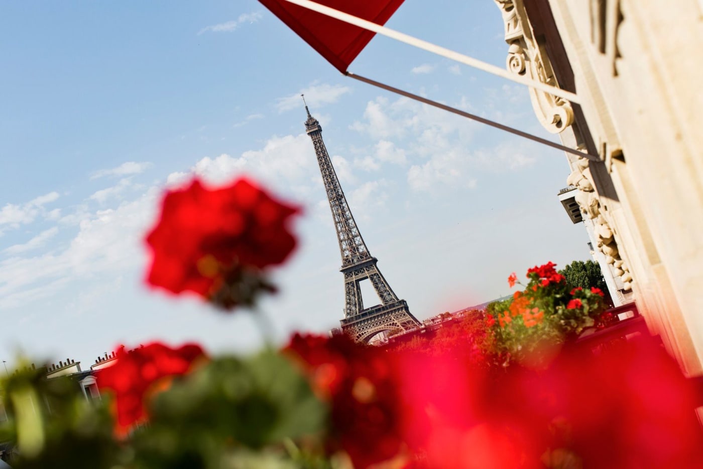 The red geraniums of Hôtel Plaza Athénée, the Dorchester Collection palace hotel on avenue Montaigne, with the Eiffel Tower in the background