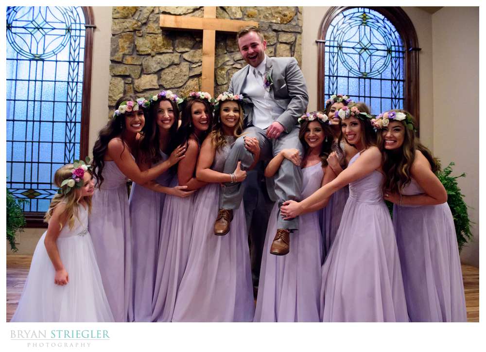 girls holding up groom