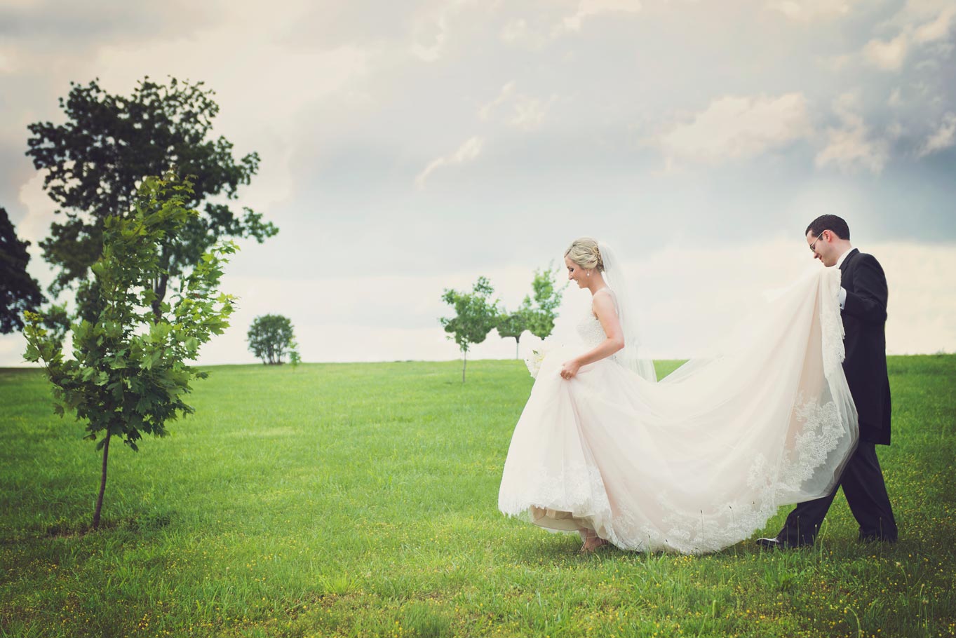 bride and groom walking through field