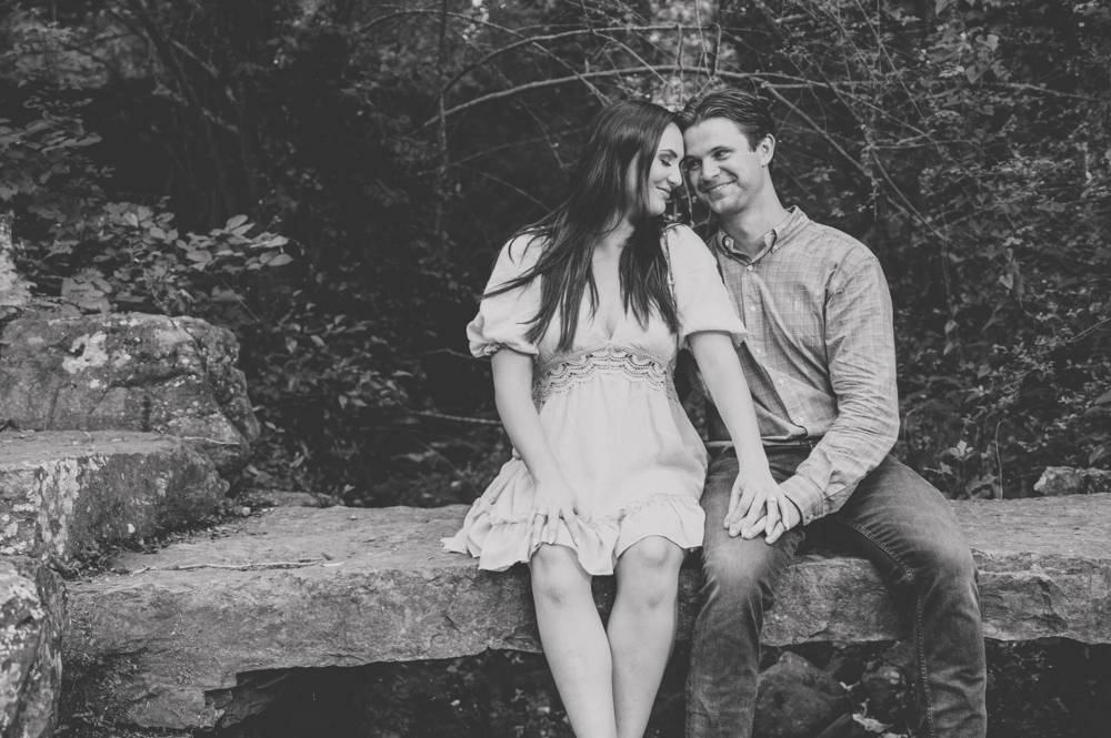 black and white image engagement photo sitting on rock