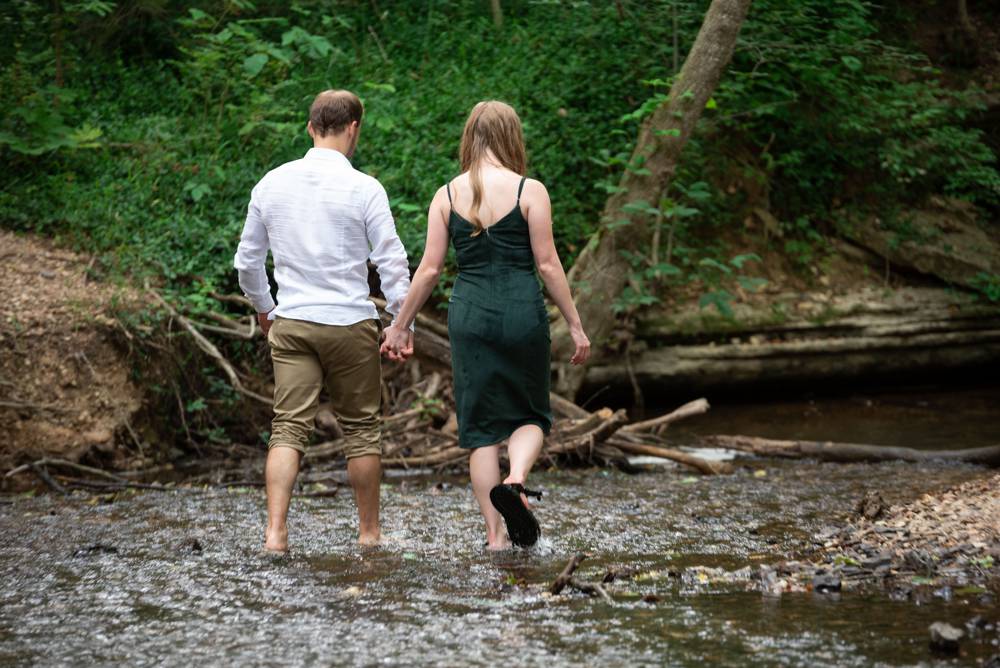 engaged couple walking in a creek