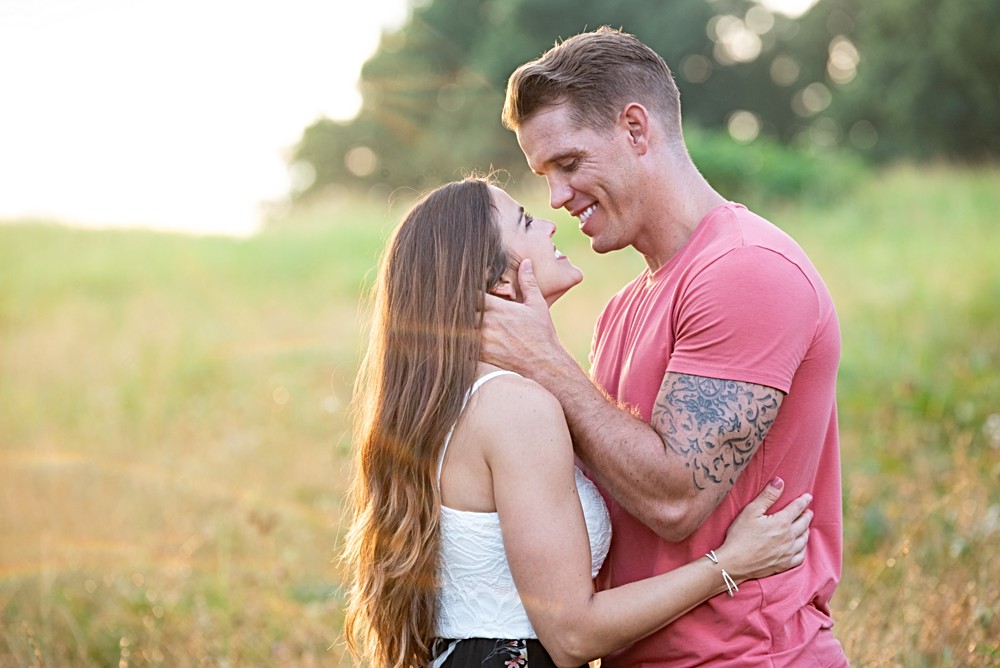 engaged couple in field with sunset