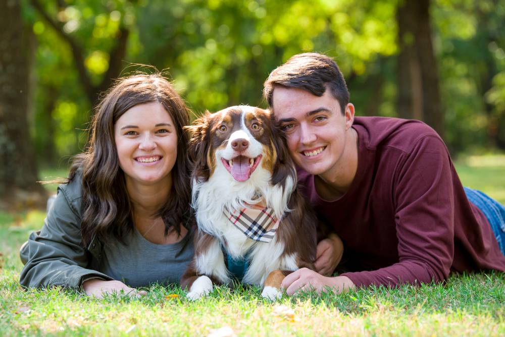 couple laying on ground with pup