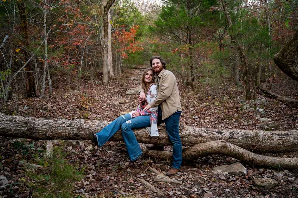 couple sitting on fallen tree in forest