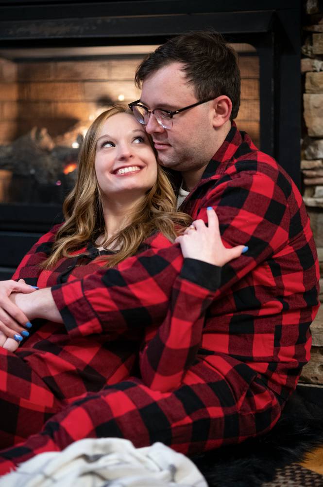 engagement photo in plaid pajamas in front of fireplace