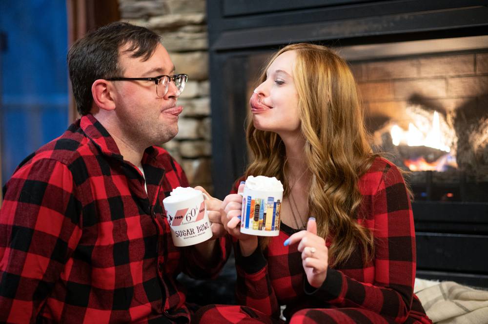 engaged couple licking whip cream off face in cabin