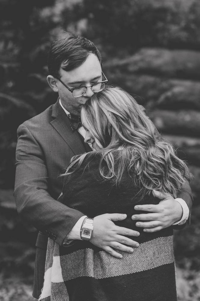 black and white engagement photo kissing her head