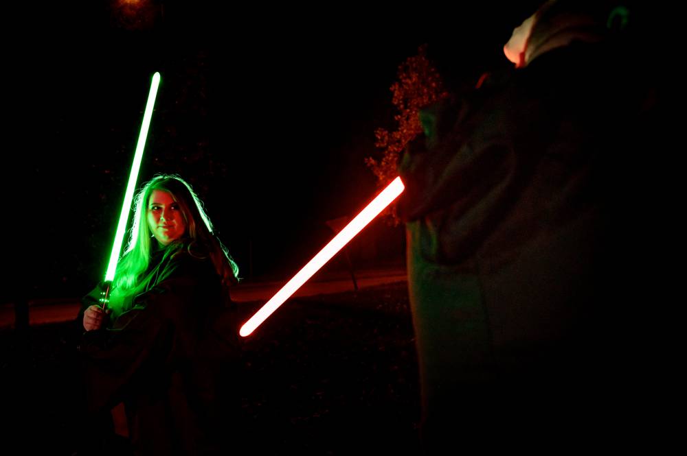 engaged couple posing with Star Wars light sabers
