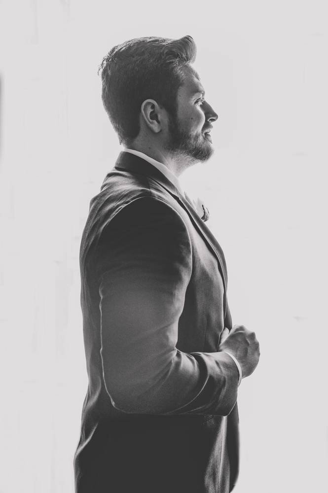 groom in front of window in Mayo Hotel black and white