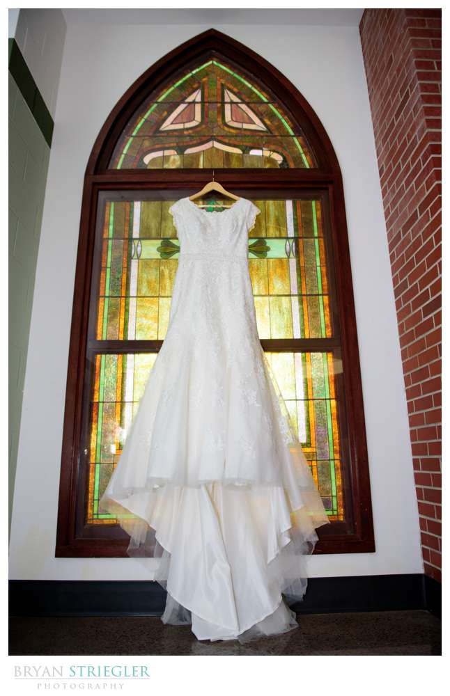 wedding dress hanging in front of stained glass