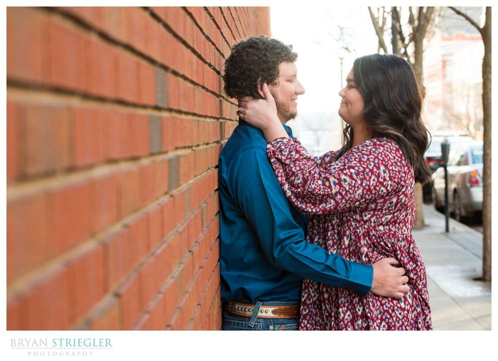couple leaning against brick wall