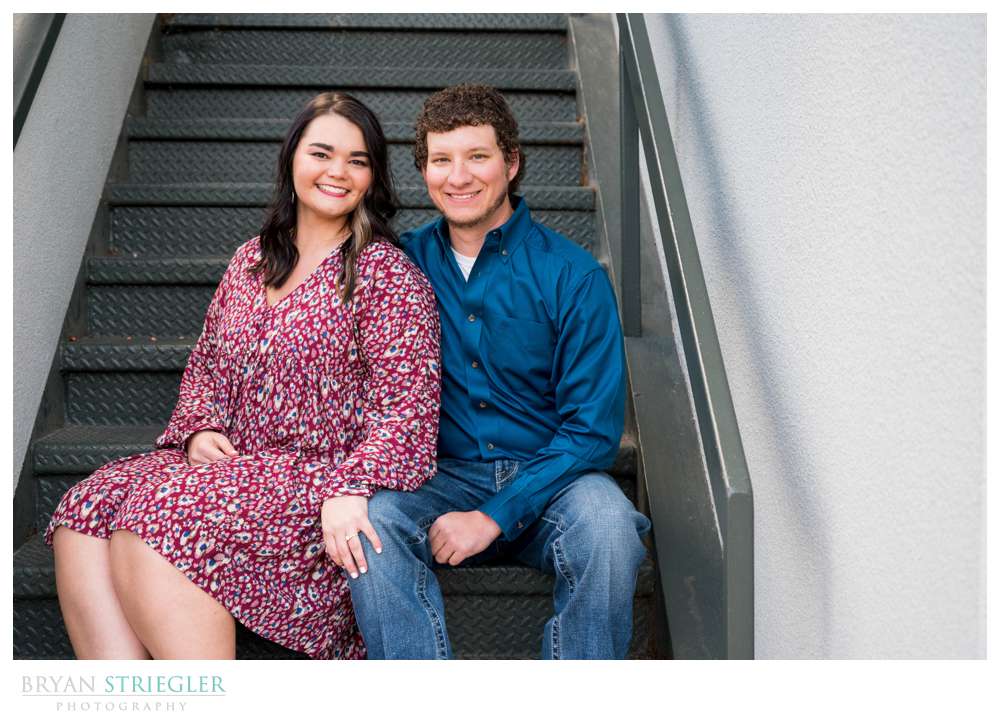 engaged couple sitting on stairs