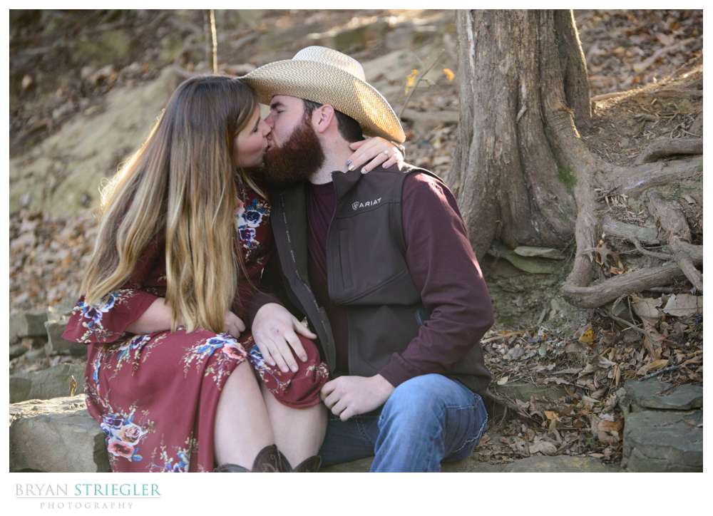 engaged couple kissing by creek