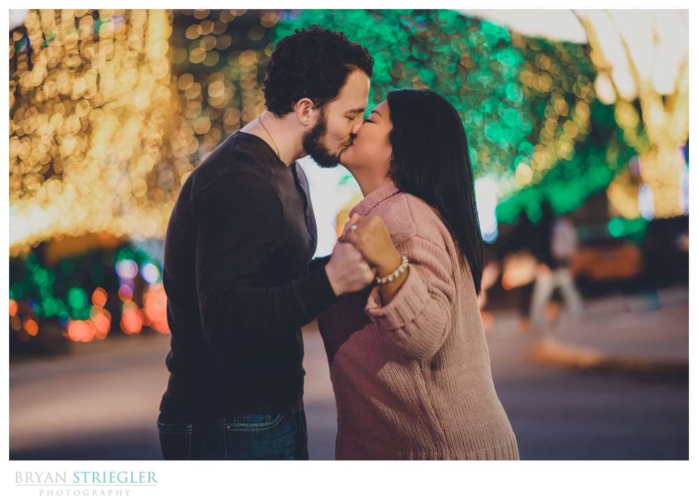 kissing in front of Christmas lights