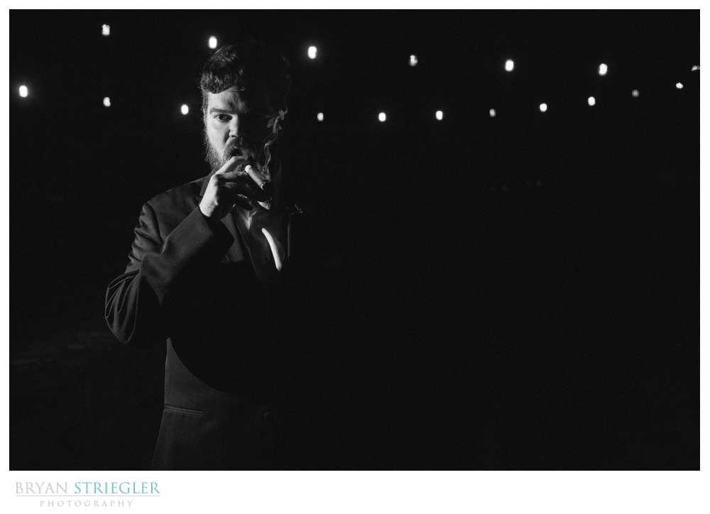 dramatic black and white of groom smoking