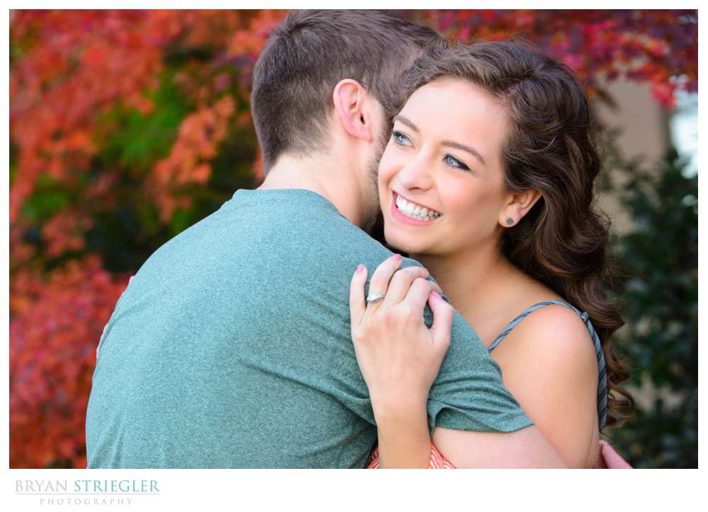 couple hugging and showing engagement ring