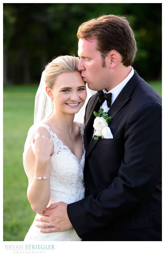groom kissing bride's forehead