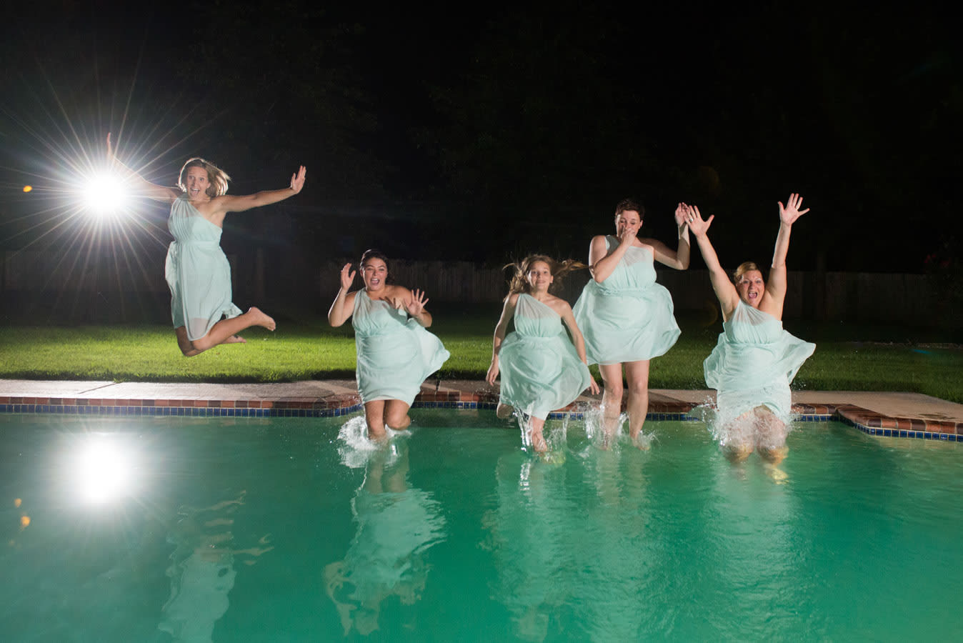Bridesmaids jumping into the pool